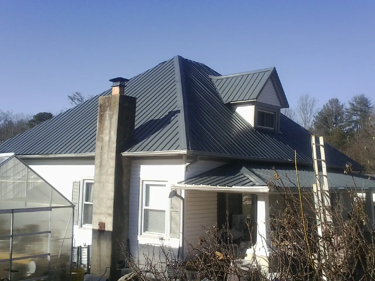 Dark blue standing seam metal roof on a white farmhouse with dormer — Slate & Tile Roof Repair by Roofing Brothers in Suches