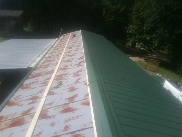 Old rusted panels beside newly installed green metal roofing — Wind Damage Roof Repair by Roofing Brothers in Suches