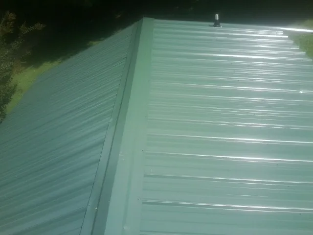 New green metal panels meeting at the ridge of a roof — Flat Roof Repair work by our crew in Suches