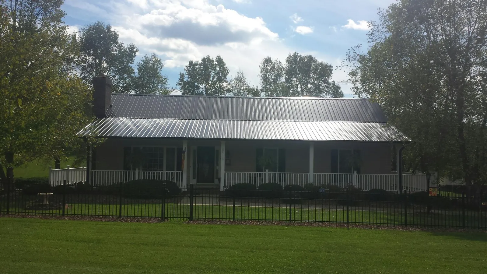 Gray metal roof on a brick ranch with a full width front porch — Gutter Guard Installation work by our crew in Suches