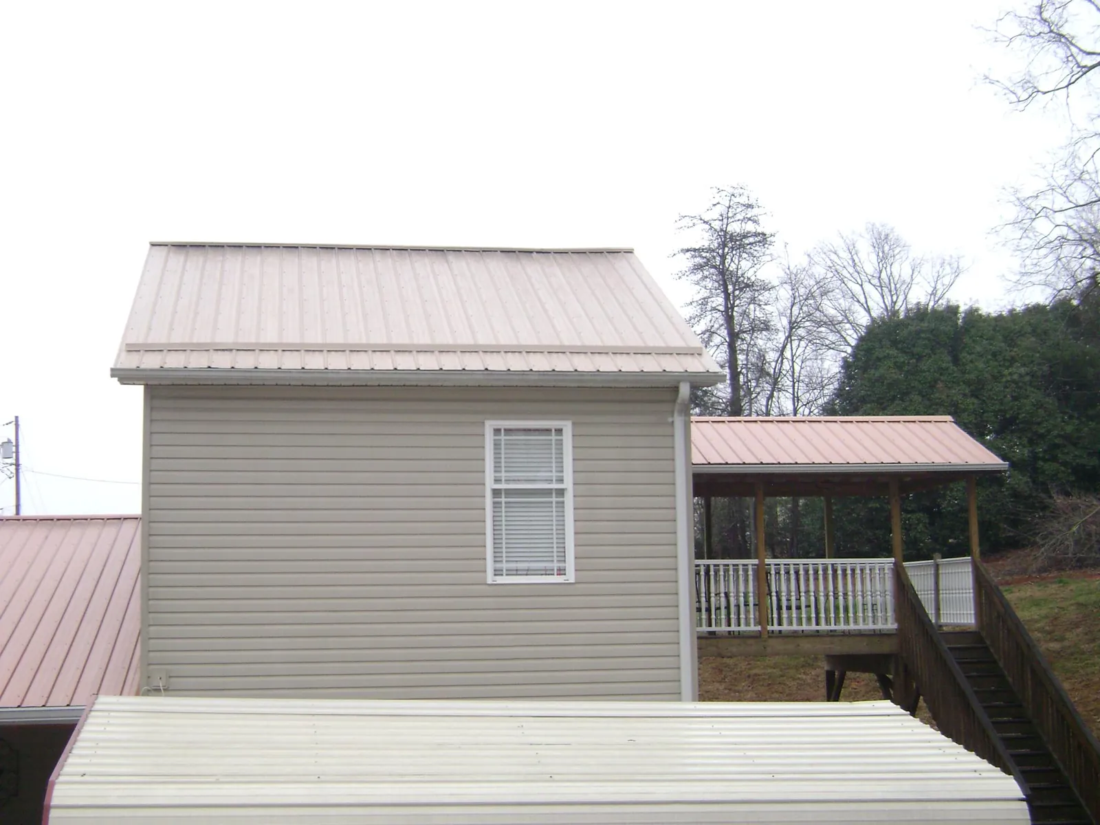 Tan metal roofs on a two story addition and attached porch in Suches