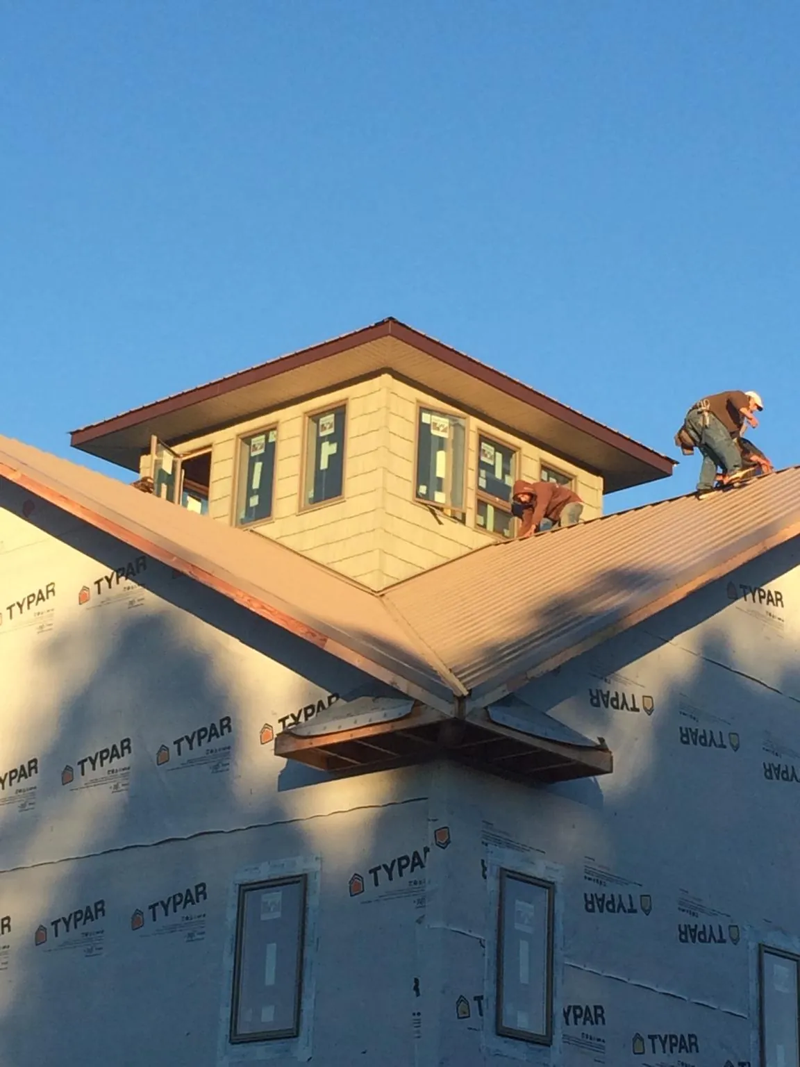 Roofers working around a rooftop cupola on a new metal roof at sunset — Roof Waterproofing in Suches by Roofing Brothers